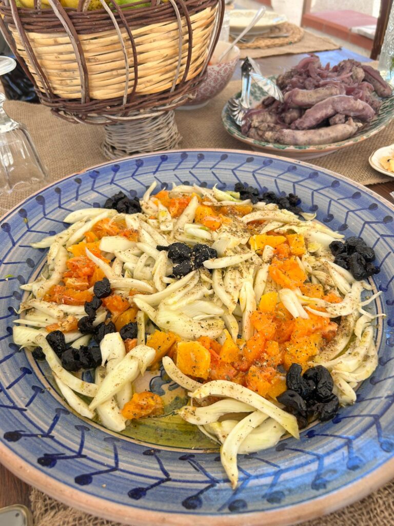 A blue plate covered with fennel, orange and olive salad