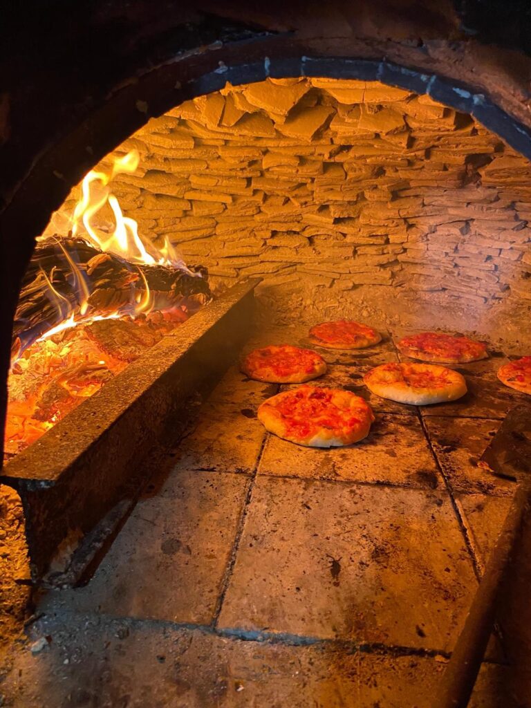 Pizzas cook in a wood fire oven in Sicily