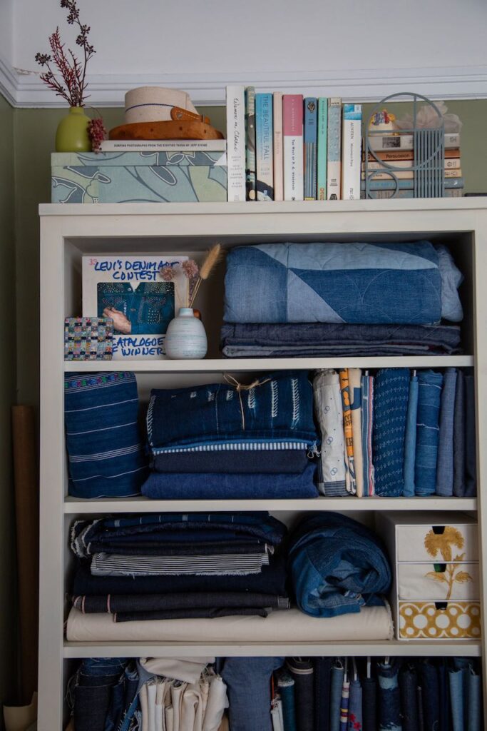A white bookcase is filled with various shades of denim fabric